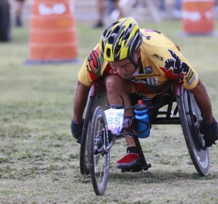 Determined wheelchair racer competing in an outdoor marathon, displaying focus and athleticism.