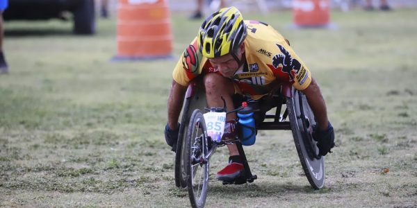 Determined wheelchair racer competing in an outdoor marathon, displaying focus and athleticism.